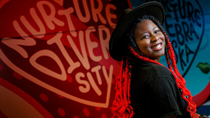 Alana Ross smiles for a photo in front of a mural in Anderson Hall.