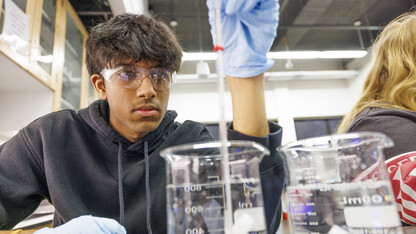 Abhi Karri checks the temperature of liquid in a beaker in a laboratory exercise.