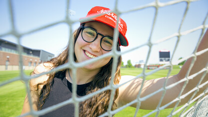 Photo by Kristen Labadie // Cece Villa, Husker soccer goalkeeper, smiles for a photo through the net of the goal.
