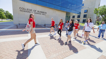 Emma Georgia walks backwards in front of the College of Business as she leads a New Student Enrollment group across campus on May 29.