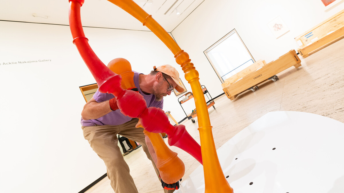 Delan Lonowski, on-call exhibition technician for the Sheldon Museum of Art, fits one of the smaller pieces of Niho Kozuru's sculpture, "Transplanted," into a stand