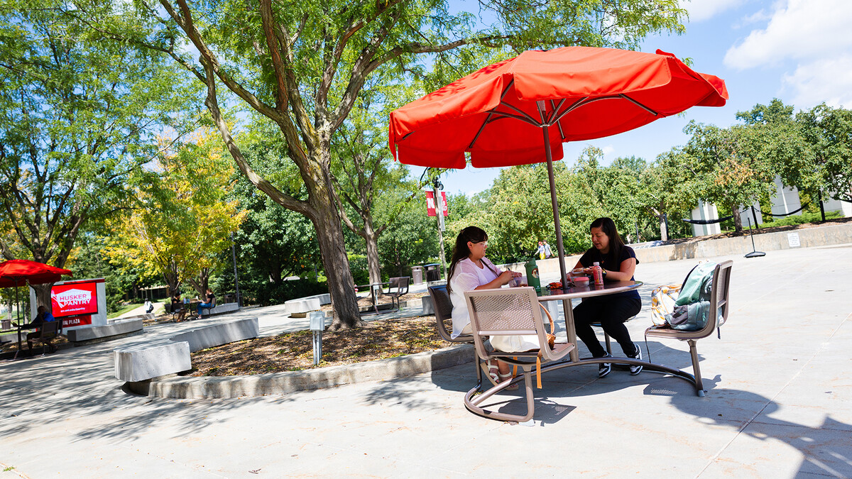 Two women having lunch on an outdoor picnic table by the Nebraska Union.