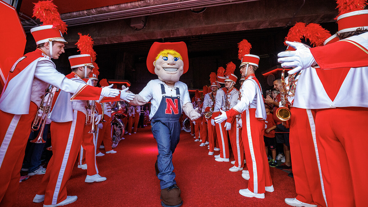 The Cornhusker Marching Band gives high fives to Herbie Husker.