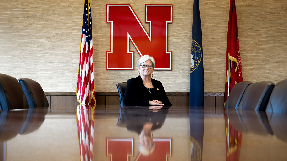 Katherine S. Ankerson, interim chancellor, sitting at the desk in the Office of the Chancellor board room, with a red Husker "N" on the wall behind her.