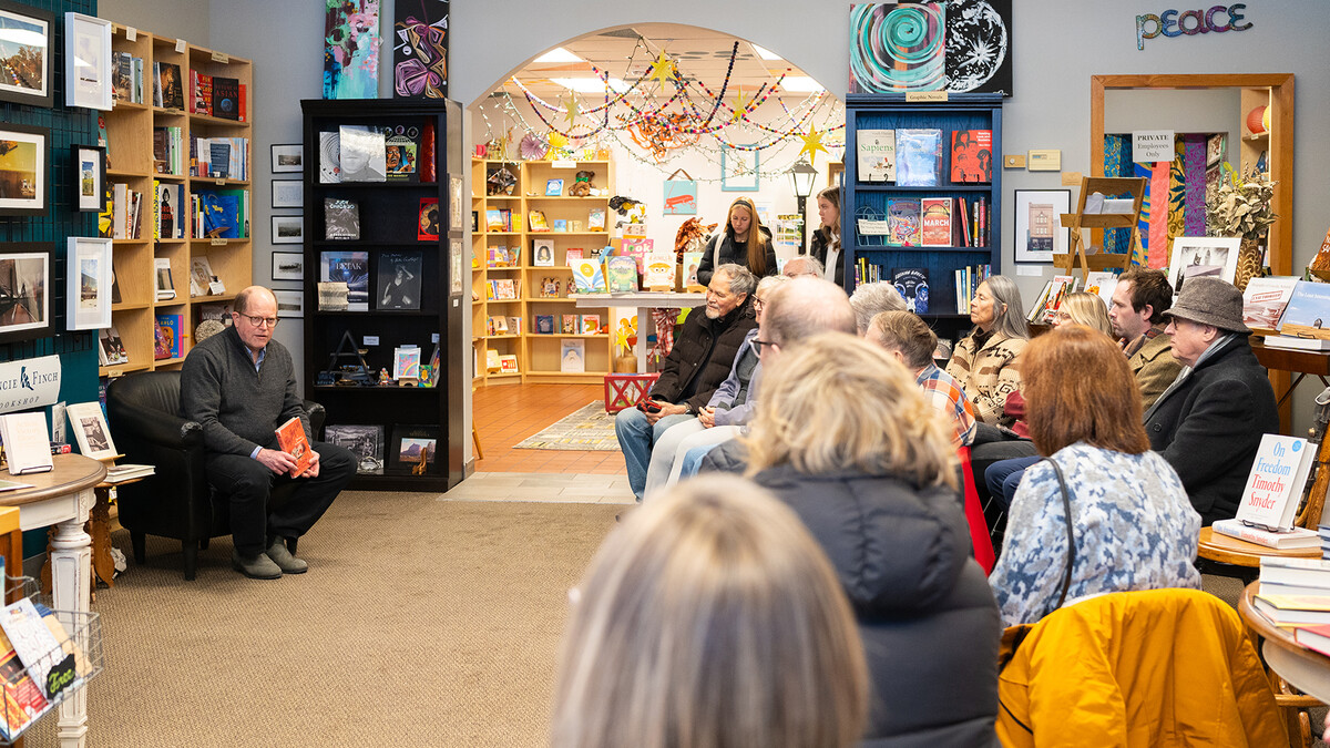 Author delivering a talk to a crowd in a bookshop.