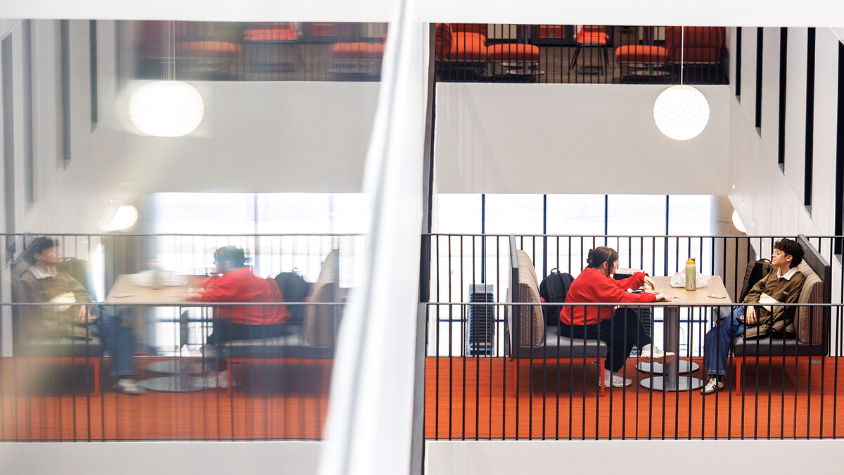tudents talk to each other at a table inside the new Fine and Performing Arts Building.