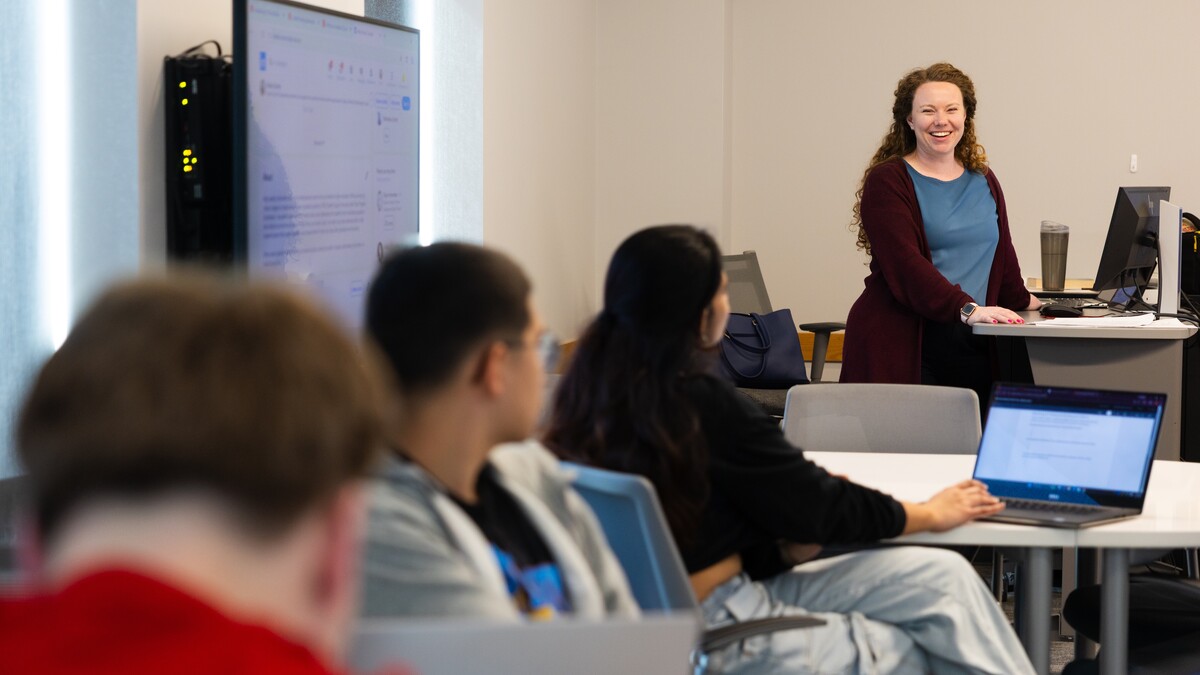 A woman stands in front of a classroom of students.