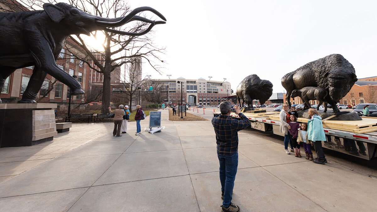 A family takes a photo in front of bronze bison sculptures created by Nebraska artist Gary Staab.