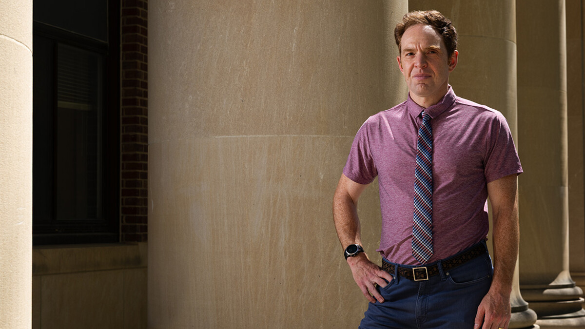 Max Mueller is photographed near a large stone column outside a building.