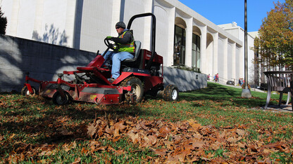Tim Herron, a landscape assistant with landscape services, mulches leaves into the grass on the east side of Sheldon Museum of Art on Nov. 8. The university recently expanded it's sustainability practices by partnering with Big Red Worms on leaf recycling.