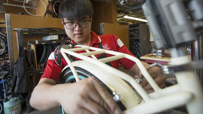 Kam Loong, a student employee, adjusts the rear brake on a Schwinn cruiser in the campus bike shop.