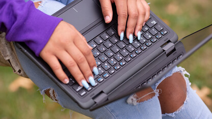 A person's hands on a black laptop.