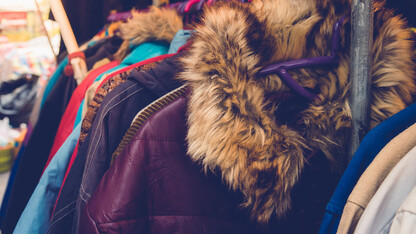 Warm winter coats hang on a coat bar.