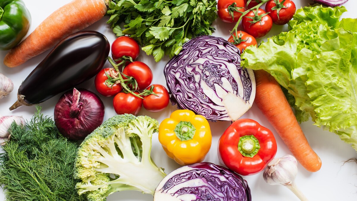 Colorful vegetables including carrots, peppers, tomatoes and lettuce are seen on a table.