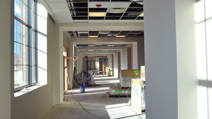 A construction worker sands drywall in a redesigned 4-H Building hallway.