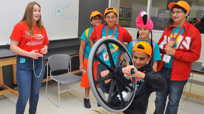 Savanna McDonald (left), a senior physics major from Omaha, shows Science Olympiad competitors from Florida how a gyroscope works during the STEM Expo in Jorgensen Hall on May 15.