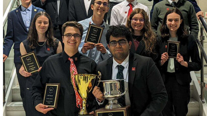 Image of Nebraska Debate Team members holding trophies and awards earned at the national competition.
