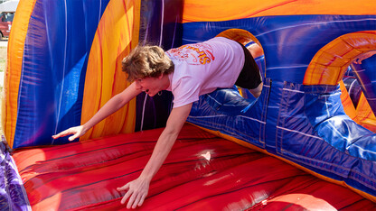 Brady McGerr braces himself with outstretched arms while crawling through the hole of an inflatable obstacle course