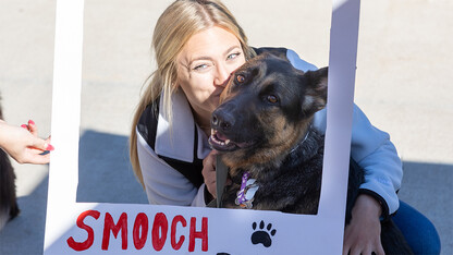 A dog owner kisses her canine while framed by a "Smooch Your Pooch" border