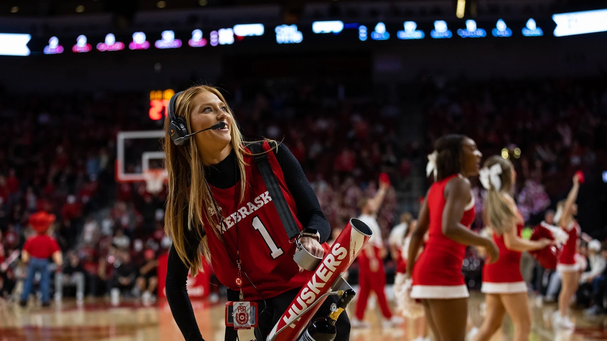 A student intern holds a T-shirt cannon on the court in Pinnacle Bank Arena.