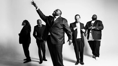 Five men — members of Big Wade and Black Swan Theory — stand in black suits against a white background.