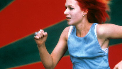 Image of a woman running in front of a red and black striped wall.