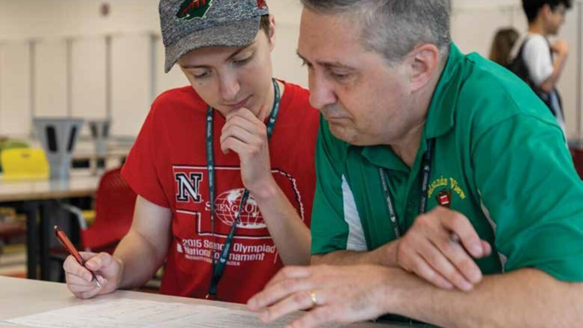 A volunteer works with a student during a Science Olympiad.