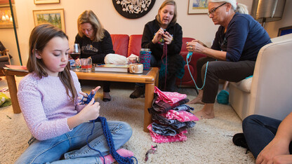 Nylah Mossop (left) uses her fingers to knit a scarf during the launch of the "Scarves for Kids" project on Nov. 20. The event was organized by Jo Ann Emerson (right) and Sandra Williams (not pictured). Other participants included (left of Emerson) Amanda Gailey, associate professor of English, and Patsy Koch Johns.