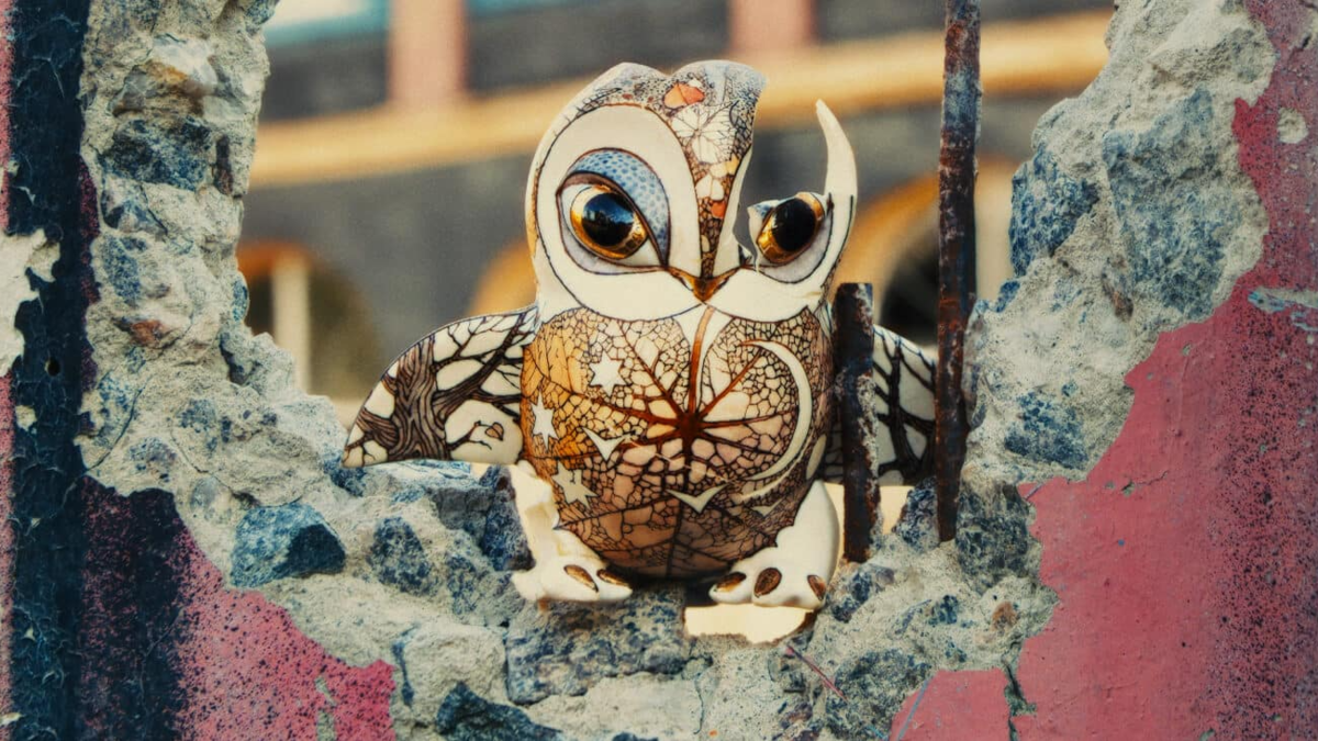 A film still from "Porcelain War" shows a ceramic painted owl with a bullet hole.