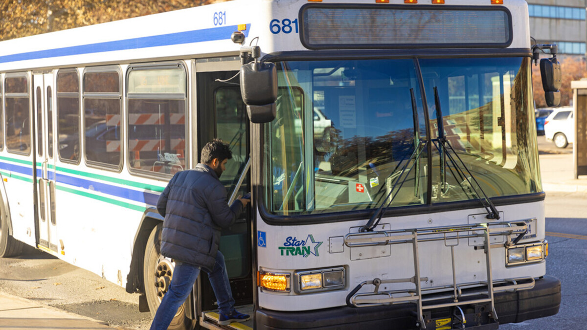 A man boards a white StarTran bus near campus.
