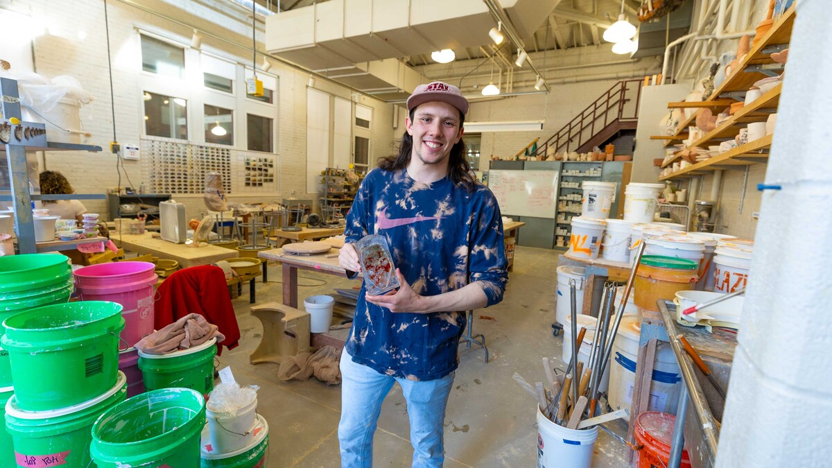 Levi Robertson poses in a Richards Hall studio with a small glass sculpture he created. 