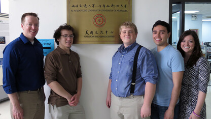 Members of the UNL Speech and Debate team delegation stand next to a plaque at the University of Nebraska's American Exchange Center at Xi'an Jiaotong University in China.