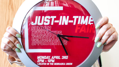 student holding clock with Just-In-Time fair details on the clock face.