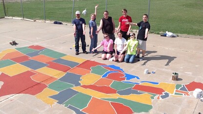 UNL students who are part of the Geography Student Organization pose by the nearly complete U.S. map painted on a Scribner-Snyder Community Schools playground.