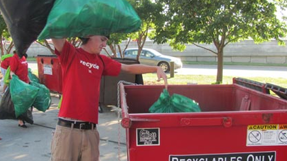 A volunteer places recyclable materials in a bin during the 2011 game against Michigan State.