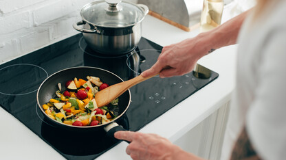 Colorful vegetables are being sautéed in a skillet.