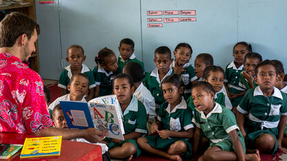 A Peace Corps worker reads to students in Fiji.