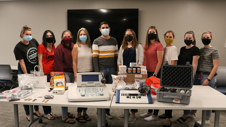Dr. Marvin Gonzalez (center), poses alongside professor of practice Stacie Ray, assistant professor of practice Hannah Ditmars, and seven Husker audiology students, with a table full of audiology equipment and supplies sent to Nicaragua for Marvin and his