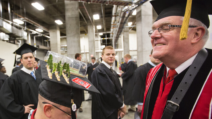 College of Agricultural Sciences and Natural Resources graduate Christopher Behrns shows off his greenhouse mortarboard to Mike Carlson before commencement on Dec. 20.