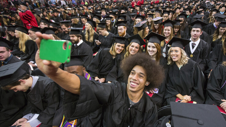 Husker Kenny Bell takes a group selfie with their phone for a group of fans in the row behind him during the procession.