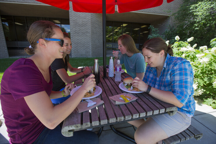 .Student employees (from left) Bria Bullard, Amber Rico, Anna Lampe and Jacey Hain sit down to eat at a table outside the East Union.