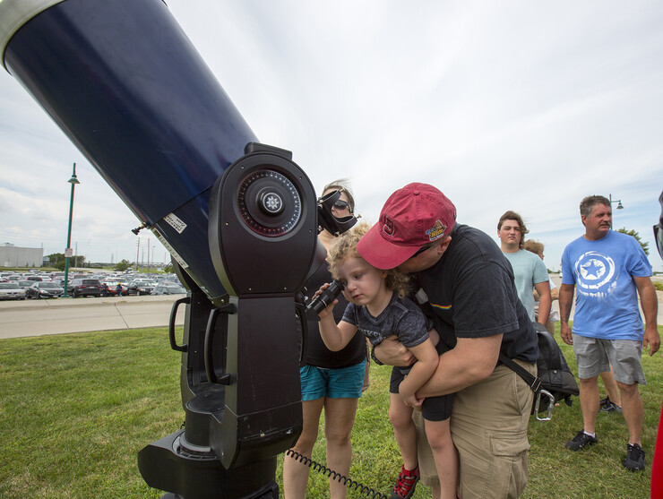 Ian Yellin hoists his daughter, Maeve, up to the eyepiece to view the solar eclipse at Hawks Field.