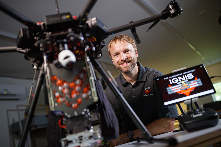 Carrick Detweiler sits next to the Drone Amplified Ignis drone system, which can be used to drop specialized balls that ignite and create back burns used to fight wildfires. The drone is among the patents earned by Nebraska U researchers in 2021.