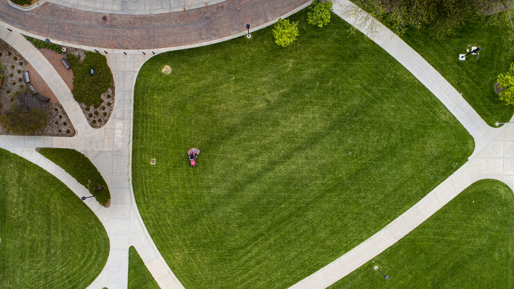 A landscape services employee goes round and round, giving a campus green space a needed trim. While many university buildings and facilities are shutdown due to COVID-19, a number of employee continue to maintain the university.
