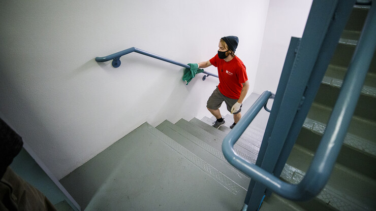 Kenny Shuman, a housing student worker, wipes down the stairway railings to keep move in clean.