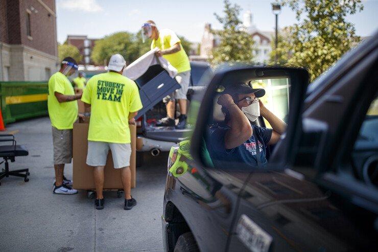 A student masks up while waiting for his turn to unload at Knoll Residence Center.