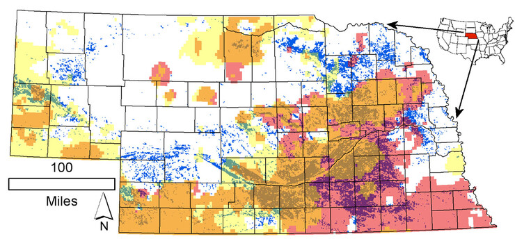 2012年灌溉土地面积为1平方公里的细胞在内布拉斯加州的分布超过了细胞面积的50%(蓝绿色点)。粉色代表年降水量下降，而黄色代表1979-2015年间灌溉季节(5 - 7月)降水量下降。棕色标记了它们的空间重叠。
