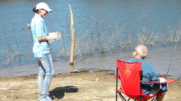 Alexis Fedele, a graduate student in the School of Natural Resources, conducts a survey with an angler at Prairie Queen Lake.