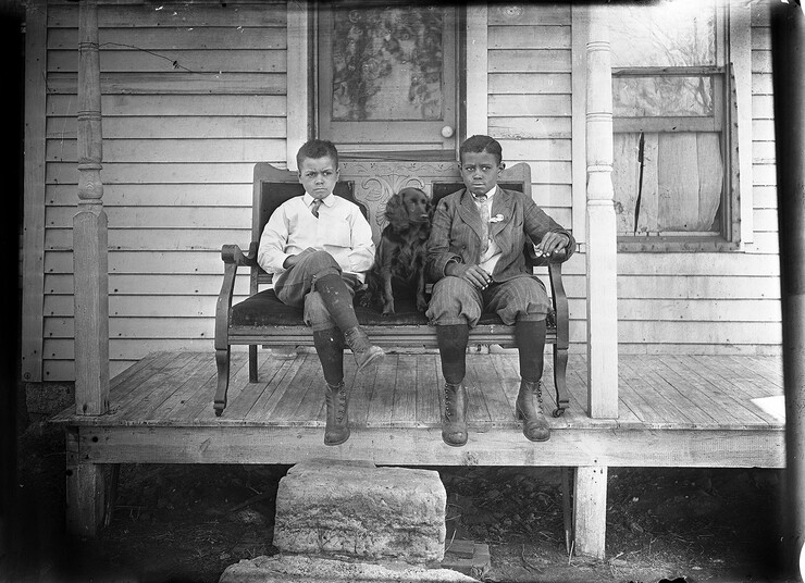 "Untitled (two boys and dog on stoop)," an undated, black and white photograph from a glass plate negative by John Johnson. The negative is part of the MONA archives collection and was a gift of Library Media Services, Lincoln, Nebraska Public Schools.
