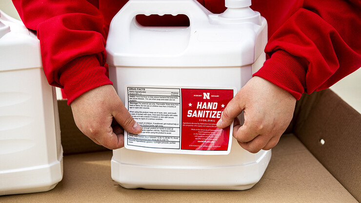 Sarah Herzinger applies labels to the hand sanitizer.
